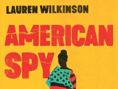 Hardcover of 'American Spy.' It features a black silhoutted figure draped in an American flag in which the blue field was replaced by green, and the white stripes were replaced by black ones, to reflect the colors of the Pan-African flag (red, black, and green). The author's name, Lauren Wilkinson, is in red text. The title is black text. It's all set against a deep yellow background.