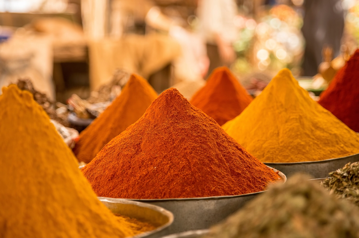 Assorted piles of spices in metal bowls for sale at an outdoor night market.