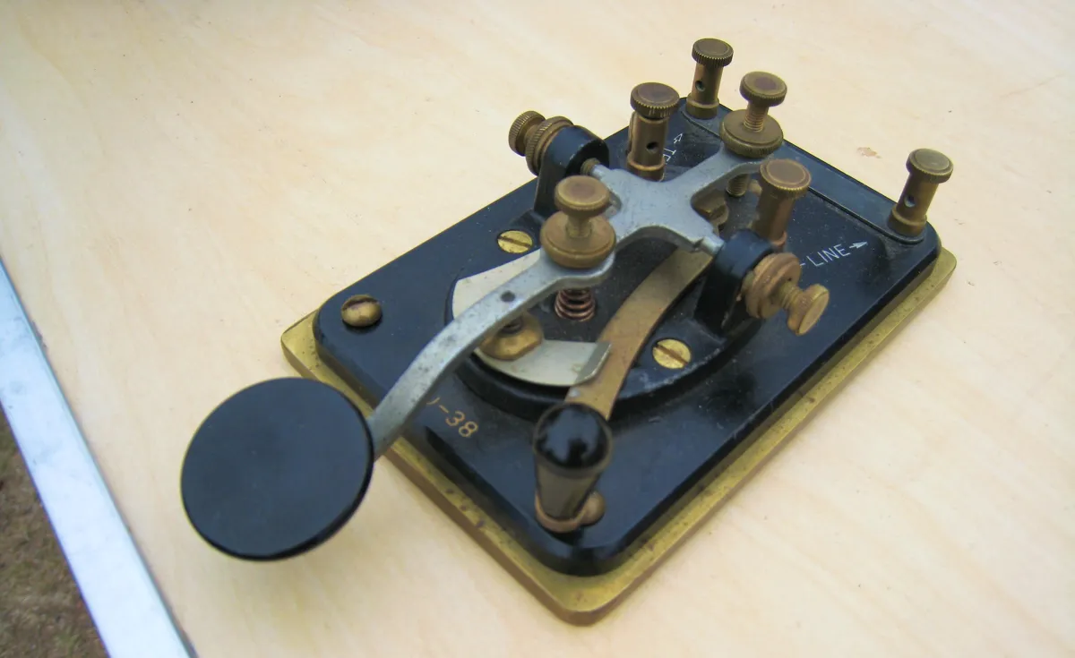 An old telegraph key made of mixed metals that look like brass steel, and a black enameled metal.