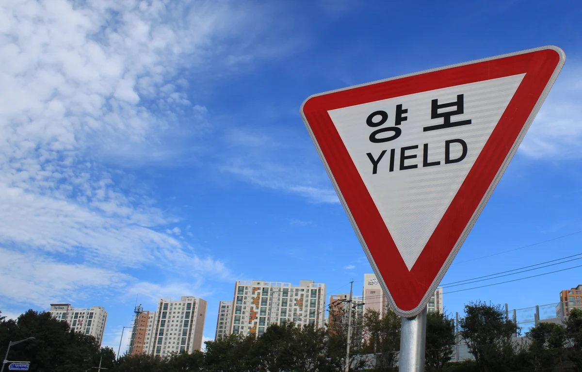 A triangle shaped sign with a thick red border. Black text that reads 